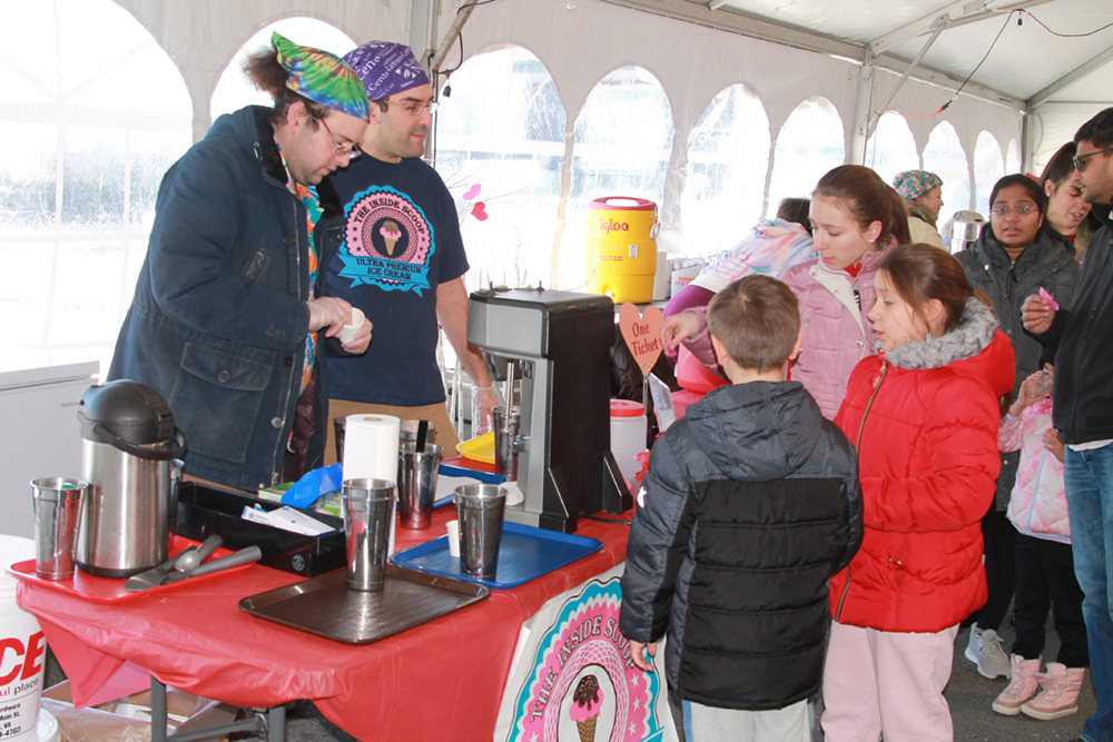two adult vendors interacting with two young customers in a white tent at the Chocolate Lovers Festival